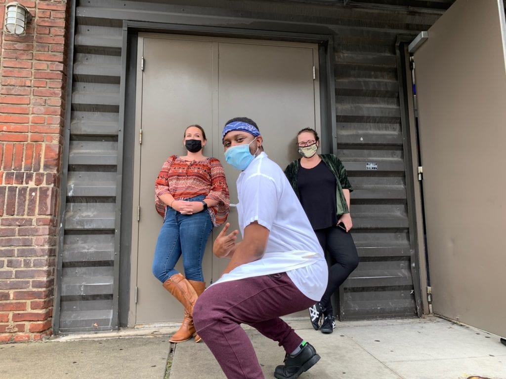 From left to right: Bridget, Cortez, and Lauren pose in front of the loading doors on 31st Street with their masks.